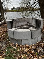 Side view of circular fire pit showing the cement blocks stacked, two levels high, with visible heat cracks and solid structure.