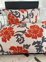 Two floral patterned feather filled pillows, one rectangular and one square, displayed against a black surface showing detailed fabric pattern and color.