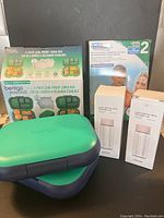 Two new Bentgo Kids Chill 2-pack leak-proof lunch boxes in teal green with navy trims, with packaging showing compartments and features.