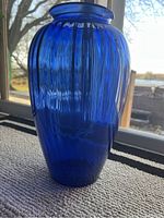 Full view of the large blue glass vase showing the ribbed texture and blue color.
