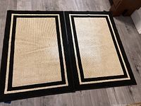 Two rectangular beige and black bordered Nautica area rugs laid on floor, showing size and color.