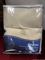 Plastic packaged cream/beige velvety plush blanket showing product branding 'Original' on blue and white label with care and comfort information.
