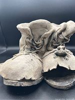 Close-up of the cement boots showing toes, laces, and frog figurine detail on one boot.
