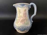 Front side view showing seated woman in pink dress and detailed blue scroll work around rim and handle.