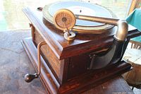 Side view showing wooden cabinet, metal crank handle, and tonearm with diaphragm horn.