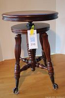 Three-quarter view of entire piano stool showing seat, base and claw feet