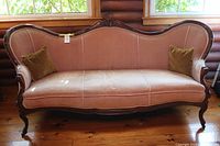 Full front view of carved Victorian settee showcasing velvet striped upholstery and carved wood frame.