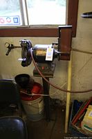 Full view of the grinder/sander unit mounted on pedestal near window, showing motor and both tool ends.