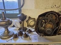 Close-up view of large metal lamp base and smaller burners with wick holders, frosted glass chimney, and ornate metal frames