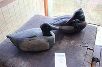 Two vintage wooden duck figures placed on a wooden surface, showing overall shape and size.