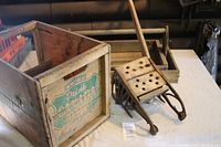 Photo showing Canada Dry wooden crate missing one side alongside the wooden and metal mop squeezer with a lever handle.