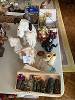 Top down image displaying all antique carvings and figurines on the table, including dog figurine, carved statues, Buddha, and small box set.