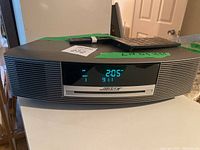 Front view of Bose Wave audio system powered on displaying time and FM station