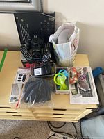 Overall view of all items on dresser including Canon camera, remote controls, fans, phone lens kit, carrying case, and decorative items.