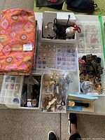 Overview of patterned jewelry roll, clear compartment boxes with earrings, bracelets, watch straps and necklace boxes
