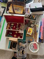 Overview of white jewelry box, wicker basket, plastic organizer, books and incense items on table