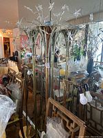 Two brass floor lamps with star LED and single bulb, standing on the floor with reflection in mirror showing details and structure.