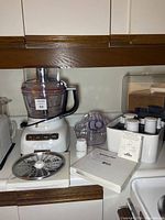 Full food processor set displayed on counter with main unit, work bowl, lid, shredding disc, attachments, and manual visible