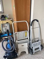 Overall lot showing blue canister vacuum on left and two folding step stools on right