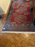 Full view of the handwoven rug on the floor showing the red background and hexagonal medallions.