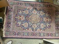 Full view of rug laid flat on carpet showing overall medallion and border design