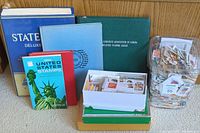 Wide view showing all stamp albums, loose stamps in containers, and boxes on the floor in front of a wooden panel wall.
