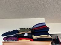 Stack of folded sweaters showing variety in color, material, and texture.