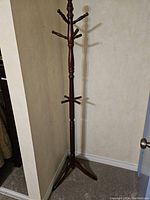 Full view of the tall solid wood coat and hat rack showing multiple tiers of pegs for hanging coats and hats.