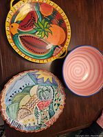 Overhead shot of all three ceramics: two platters and one bowl on a wooden surface.