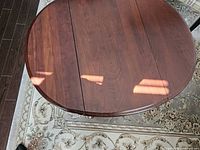 Top view showing the oval solid wood tabletop with drop leaves closed, natural wood grain visible