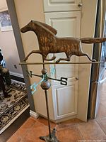 Full view of free-standing copper weather vane showing galloping horse and tripod base