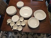 Table with all pieces of Johnson Brothers Focus Collection dinnerware laid out showing multiple bowls, dinner plates, side plates, salad plates, cups and saucers.