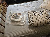 Image showing the folded quilt and one pillow sham laid on a bed with striped bedding.