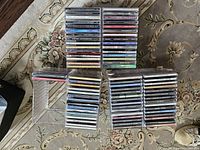 Overall view of 72 assorted music CDs stacked in three groups on a patterned carpet