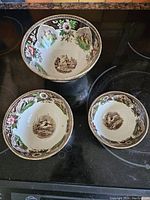 Set of three vintage footed nesting bowls displayed from above showing all three sizes and decor.