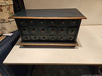 Front view of the 18-drawer apothecary chest showing all drawers, wooden knobs and painted blue finish with distressed edges