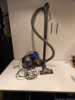 Full view of Dyson DC46 canister vacuum with hose, wand, power cord and floor tool on white table