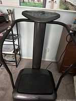 Front view of Kwikfit4u AU400 vibration plate showing platform, handles, and control panel from a standing angle.