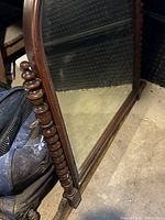 Close-up side view of antique wooden bedroom mirror showing spindle detail on the frame.