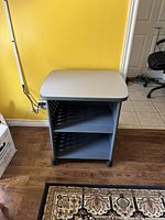 Side view of black and grey printer cart showing two shelves and wheels