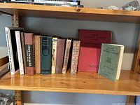 Shelf showing 11 vintage and retro books of various sizes and colors with visible wear.
