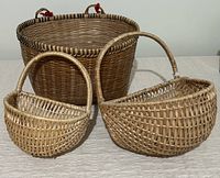 Three vintage wicker baskets together: large round basket with dark banding and two smaller handled baskets in light natural wicker