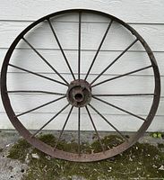 Full front view of the antique iron cart wheel showing the entire round wheel and spokes.