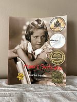 Front cover of Hana's Suitcase showing photograph of young girl, author name Karen Levine, and various awards stickers.