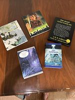 Five Tolkien-related books and music CD arranged on a wooden surface, showing all item covers.