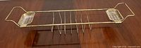 Full view of the brass bathtub caddy tray showing its rectangular shape with metal grid and two soap holders on each end.