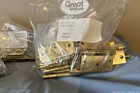 Close-up of multiple brass door hinges in a plastic zip-lock bag, showing wear and tarnishing