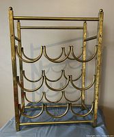Front view of brass plated wine rack showing four rows with curved holders for wine bottles.