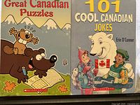 Front covers of two books: 'Great Canadian Puzzles' and '101 Cool Canadian Jokes' showing colorful cartoon illustrations representing Canadian themes.