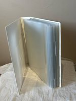 Open white 2.5 inch 3-ring binder with plastic page inserts showing worn edges and clean white cover.